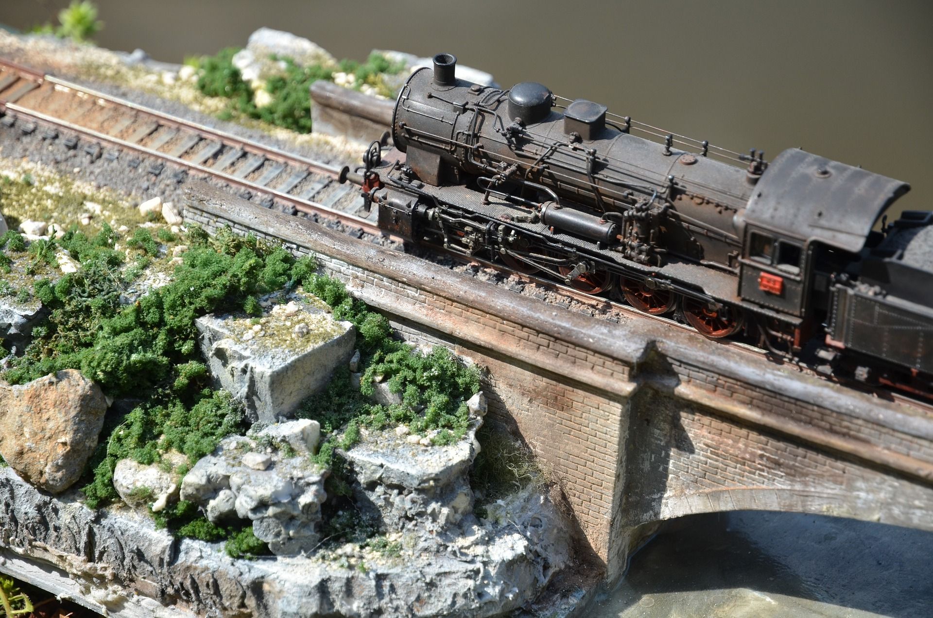 Model steam locomotive passing over a viaduct